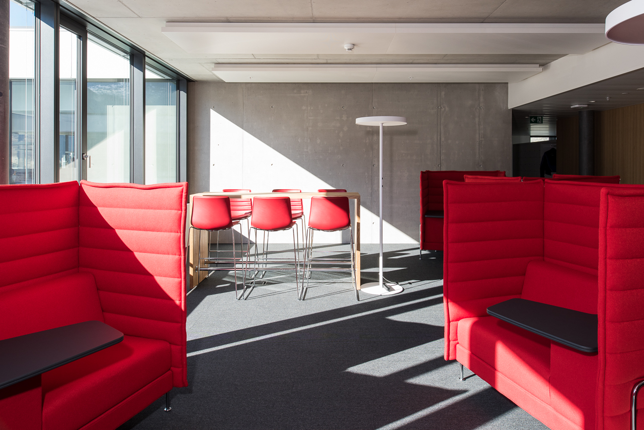 Espace de travail collaboratif avec sièges rouges et tables hautes